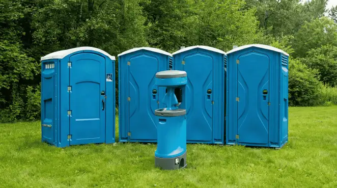 Four blue portable toilets and a matching hand washing station on grass near trees, a common sight at local outdoor events in Memphis, TN